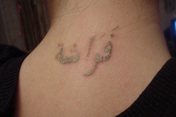 Tatuaje palabra mariposa caligrafía árabe